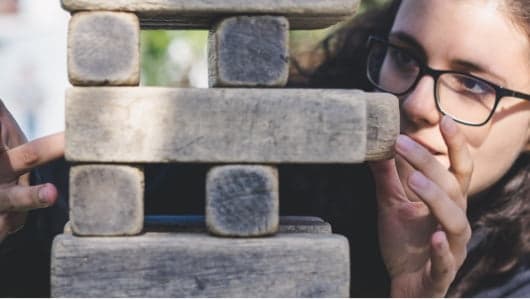 A lady in glasses playing jenga.